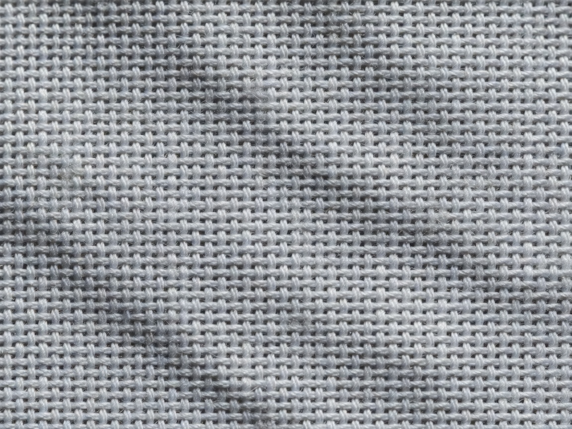 Macro photograph of plain-weave cotton fabric with raking light revealing individual threads